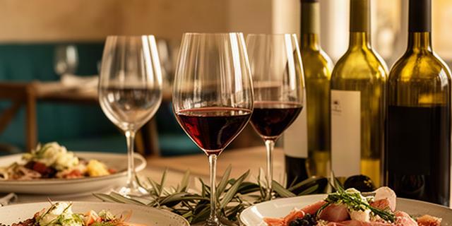 Calici e bottiglie di vino pugliese accanto a piatti della cucina di Locorotondo